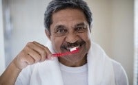 Portrait of senior man brushing teeth in bathroom