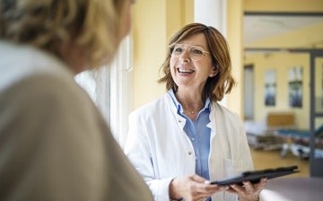 Smiling doctor with a digital tablet talking to a female patient