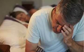 Depressed man awake in bed suffering with insomnia