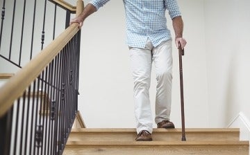 Senior man climbing downstairs with walking stick