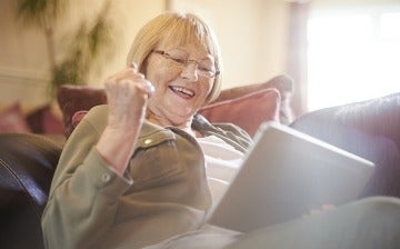 Senior woman having positive reaction while glancing at a tablet screen