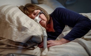 Woman in bed using a CPAP machine