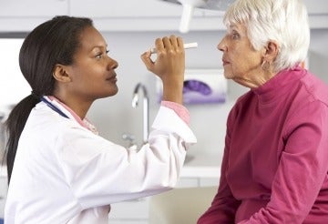 Opthamologist providing an eye exam to an elderly woman