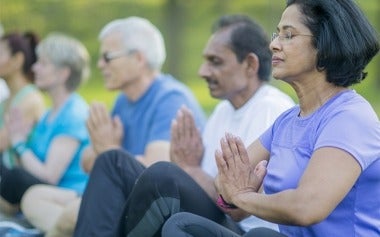 Seniors meditating and practicing yoga in the park