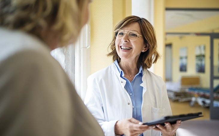 Smiling doctor with a digital tablet talking to a female patient