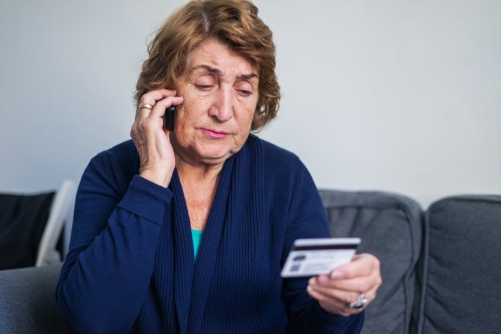 Woman talking on phone with credit card in hand